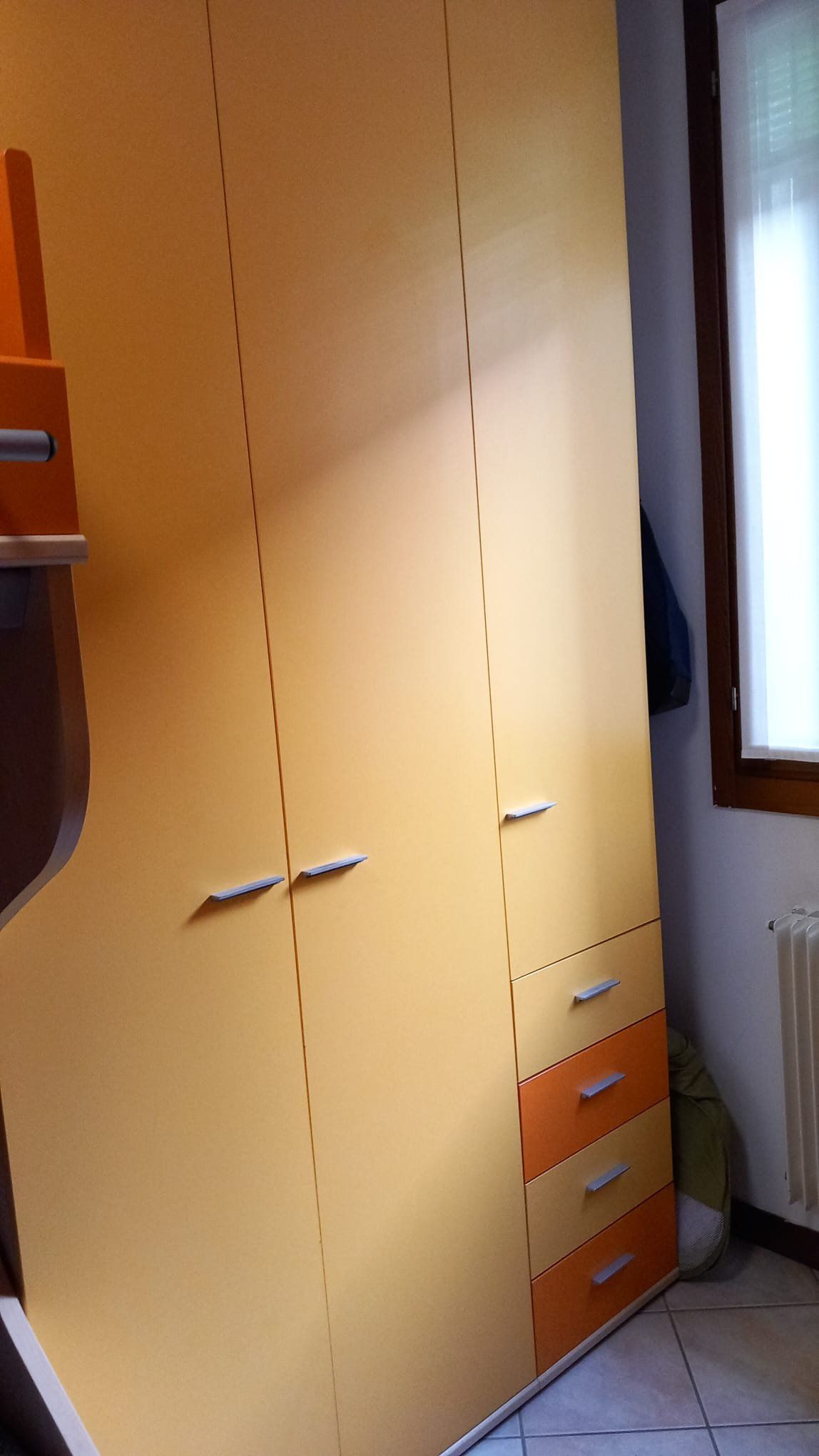 Armadio prima del restyling: ante in finitura legno chiaro e cassetti arancioni della vecchia cameretta