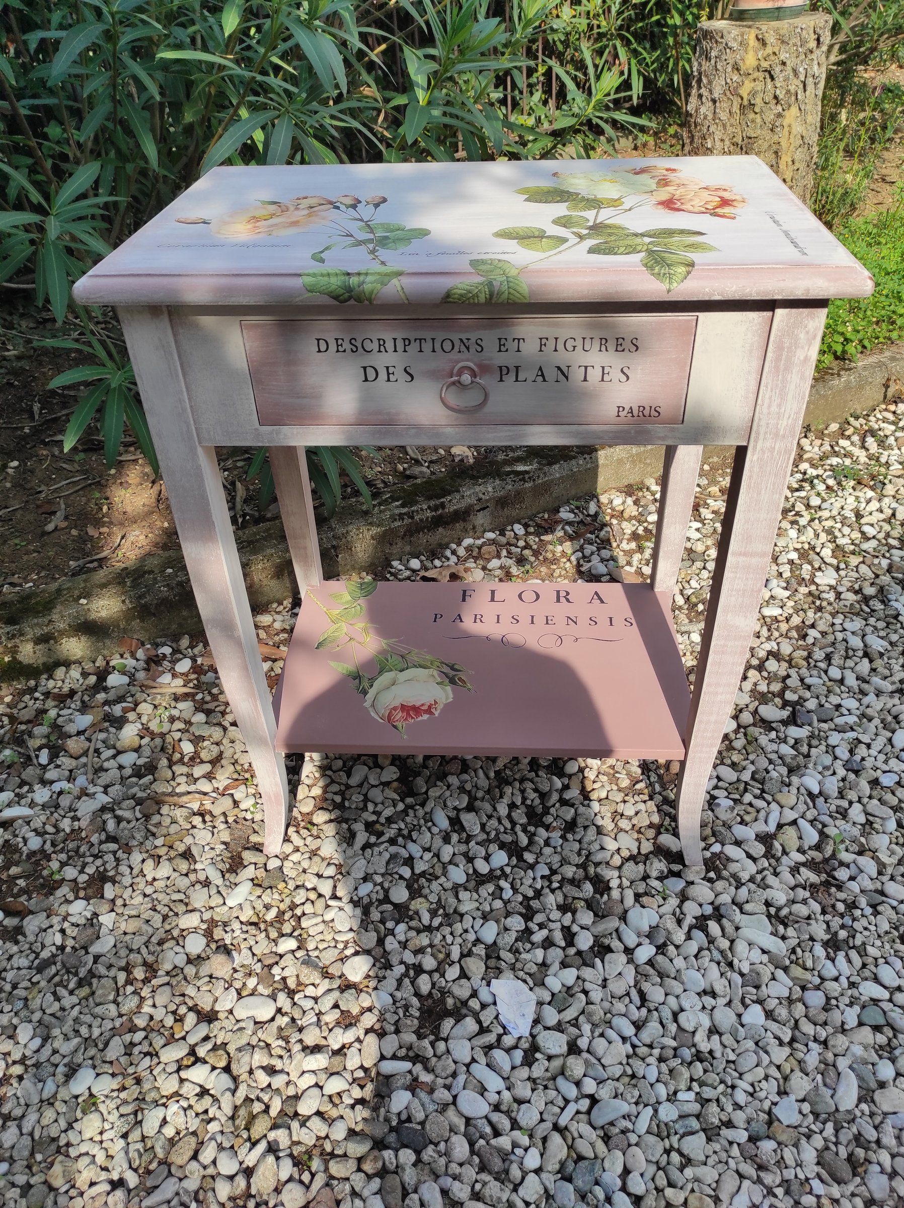 Tavolino rinnovato visto di tre quarti: piano con rose e ripiano inferiore rosa