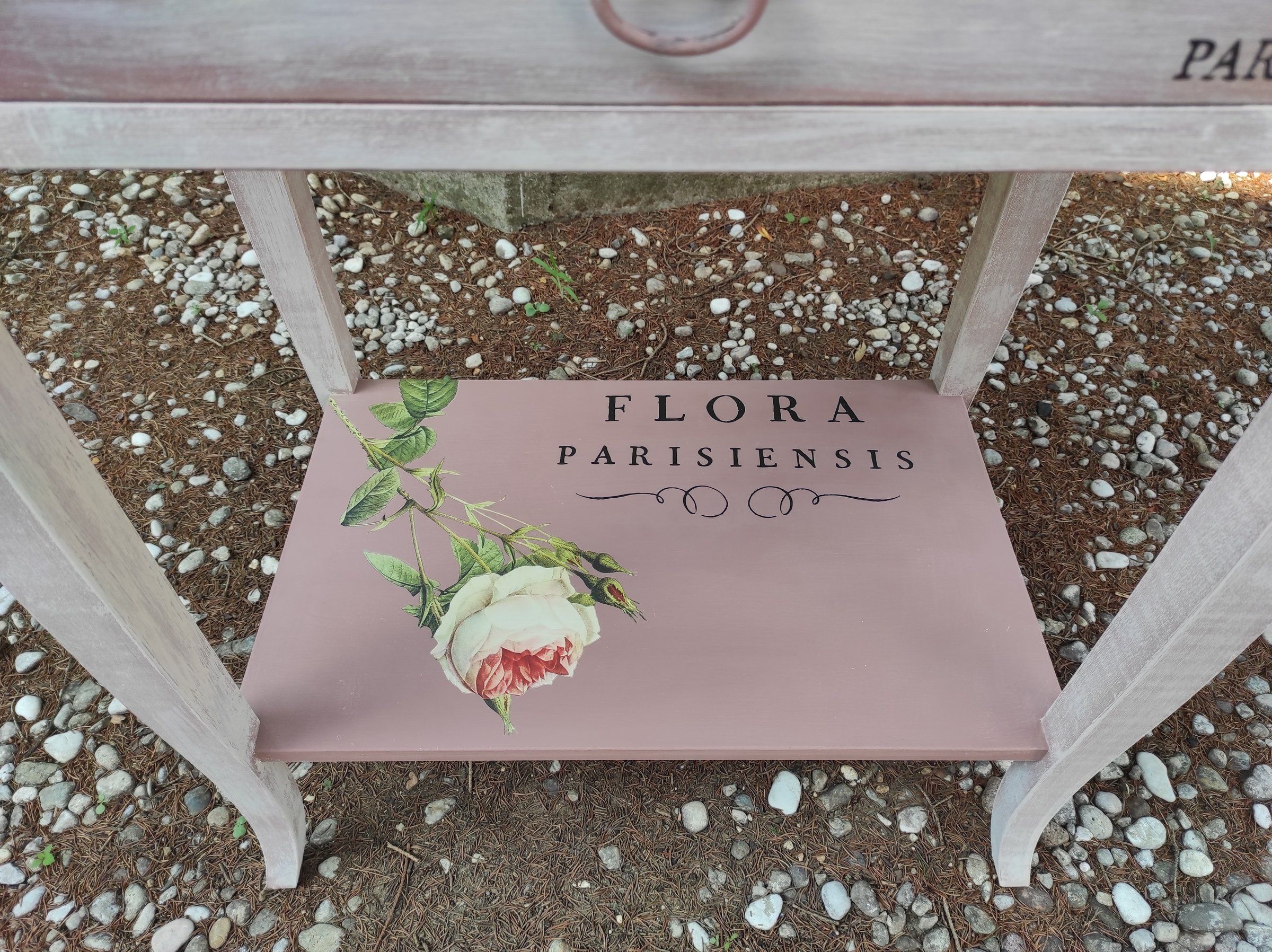 Ripiano inferiore rosa cipria con scritta in francese e una rosa