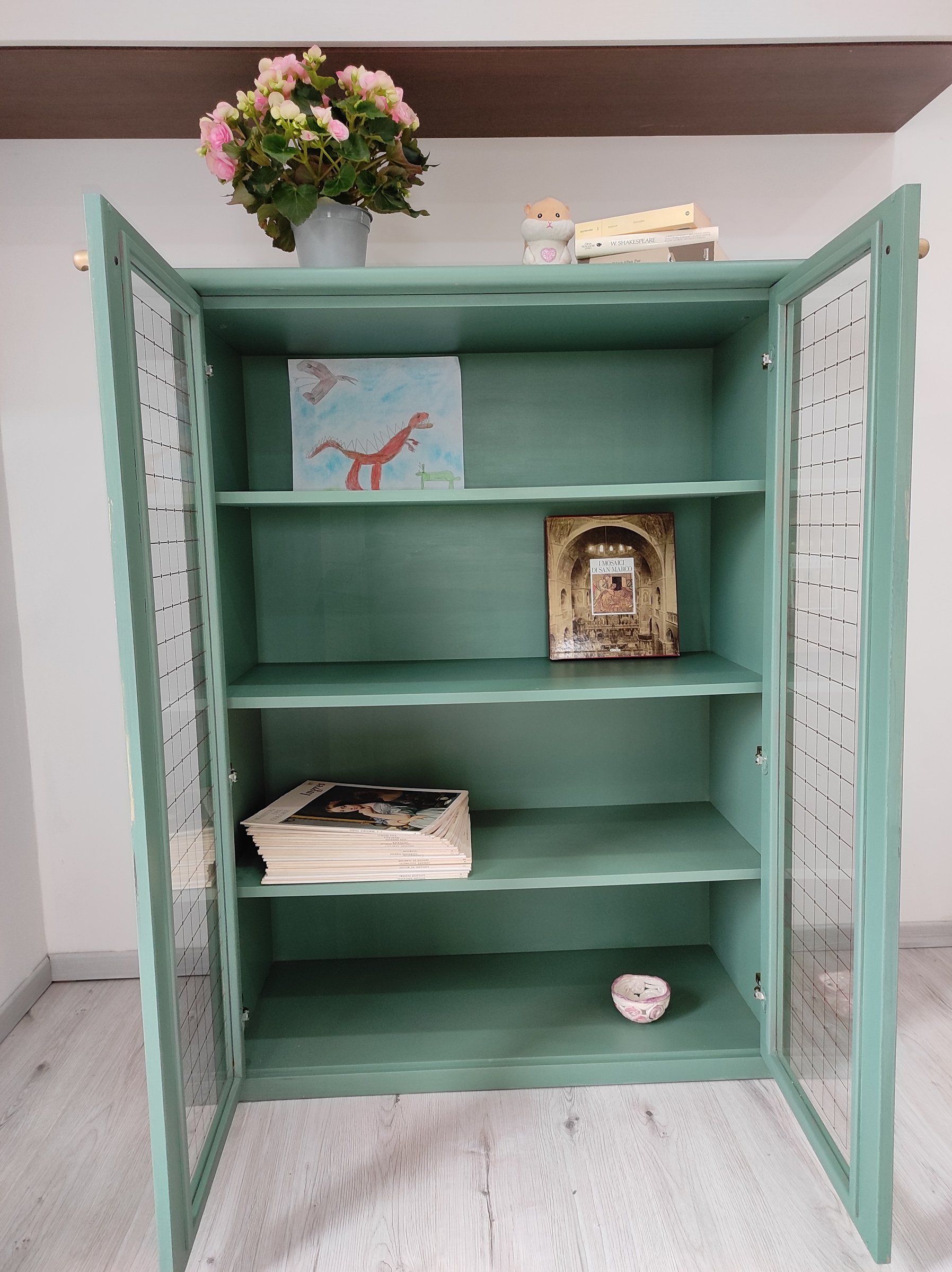 Vetrina verde con le ante aperte e l'interno dipinto dello stesso colore