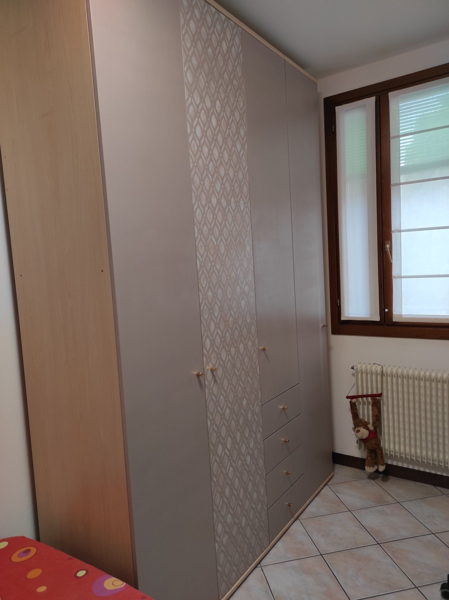 Armadio dopo il restyling nella camera degli ospiti: ante color tortora e un'anta decorata