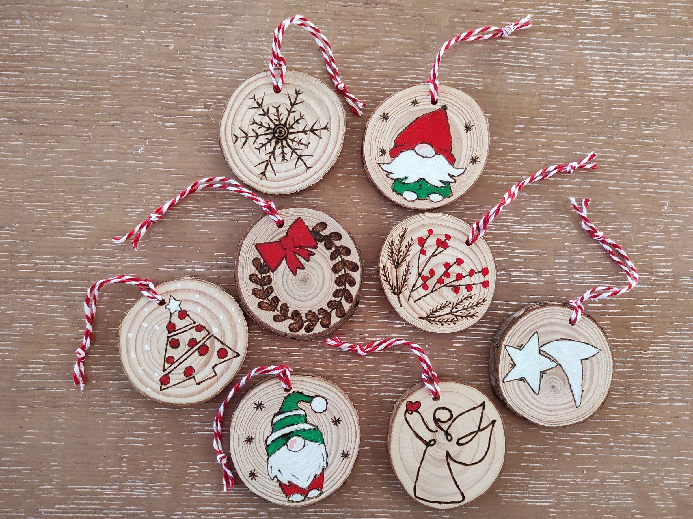 Decorazioni natalizie dipinte a mano su fette di legno: gnomo, angelo, stelle e rametti con bacche rosse