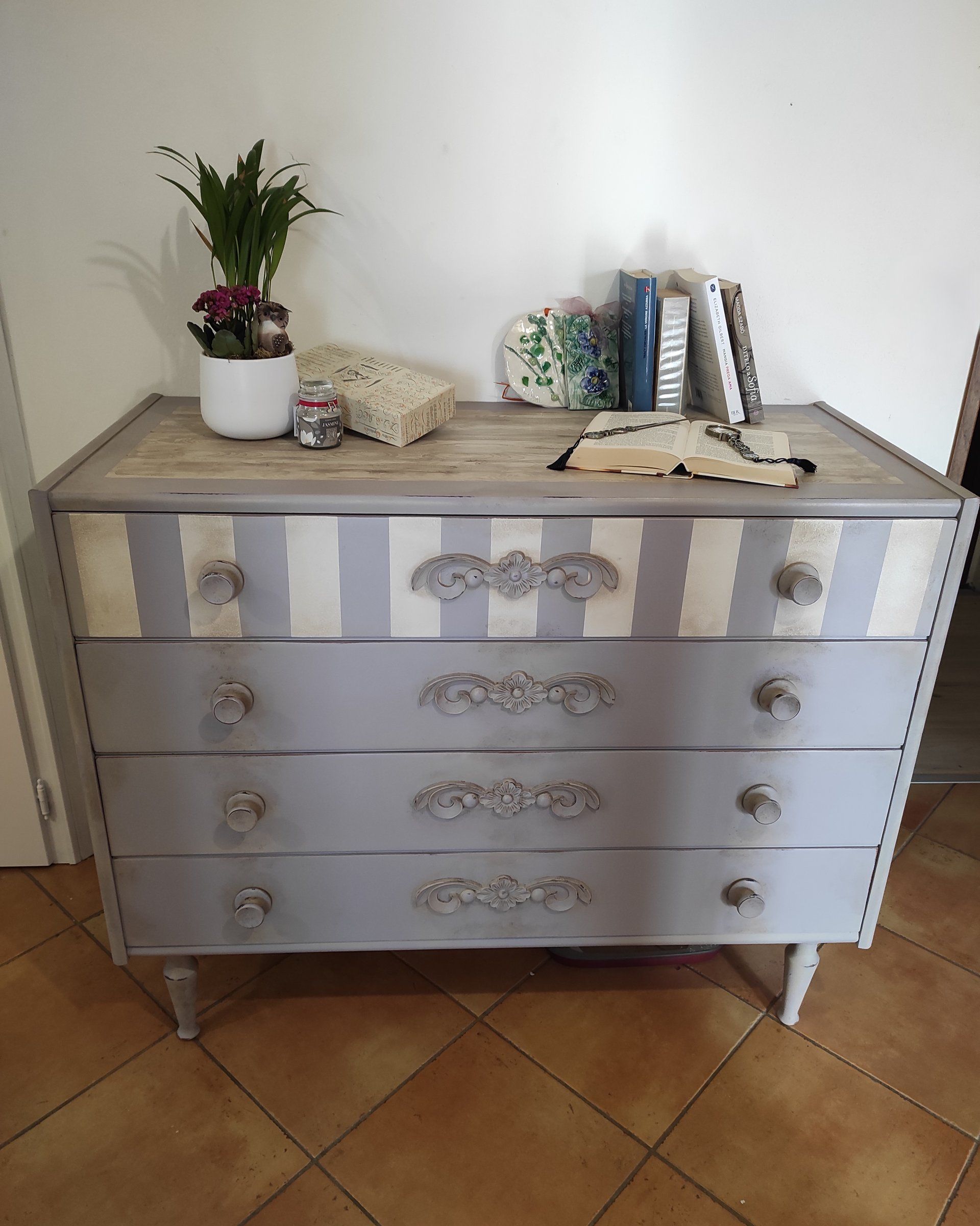 Comò di famiglia dopo il restyling: lavanda antico, primo cassetto a righe e fregi lignei applicati