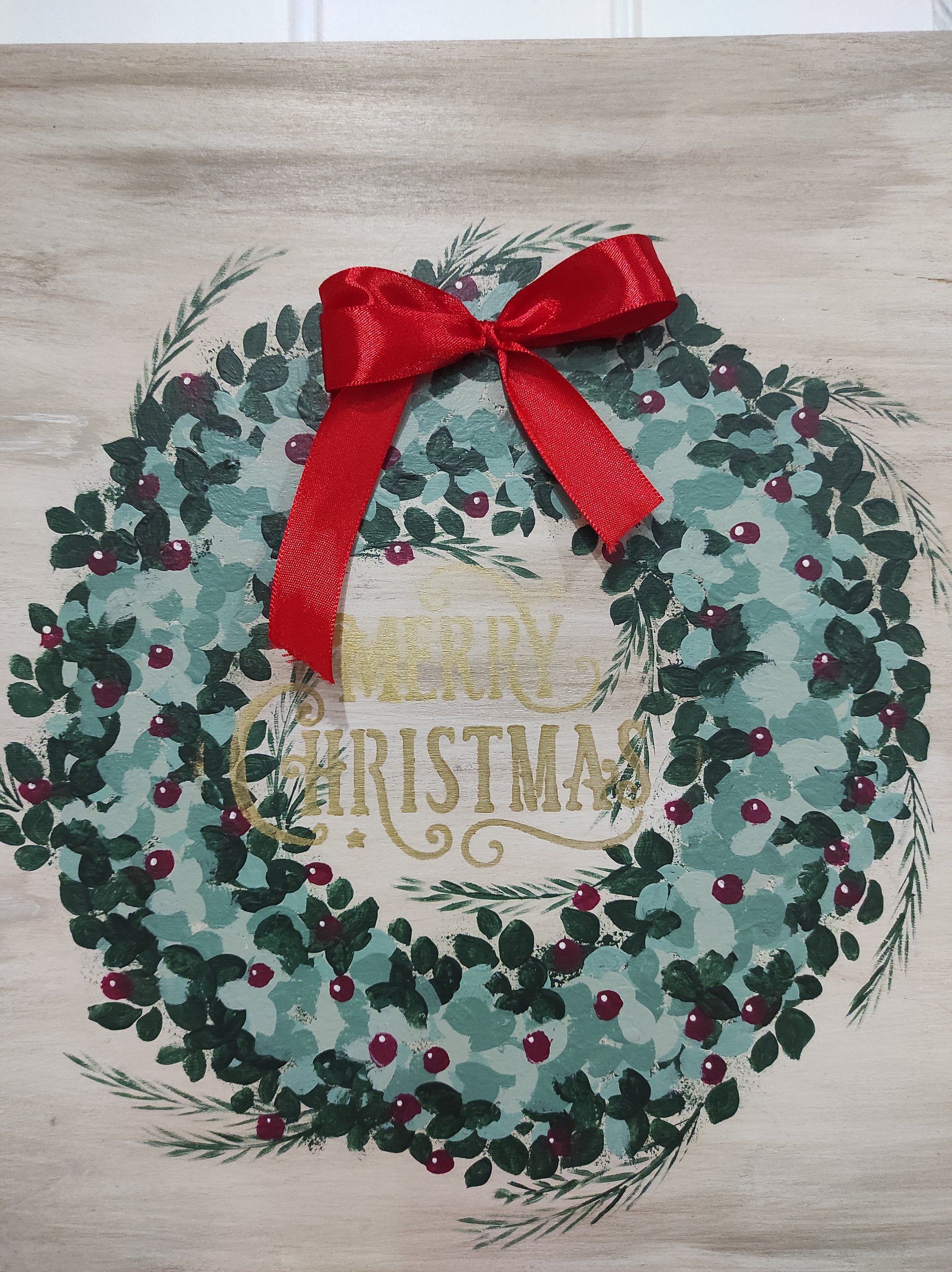 Tavola dipinta a mano con ghirlanda verde, bacche rosse, fiocco rosso e scritta Merry Christmas