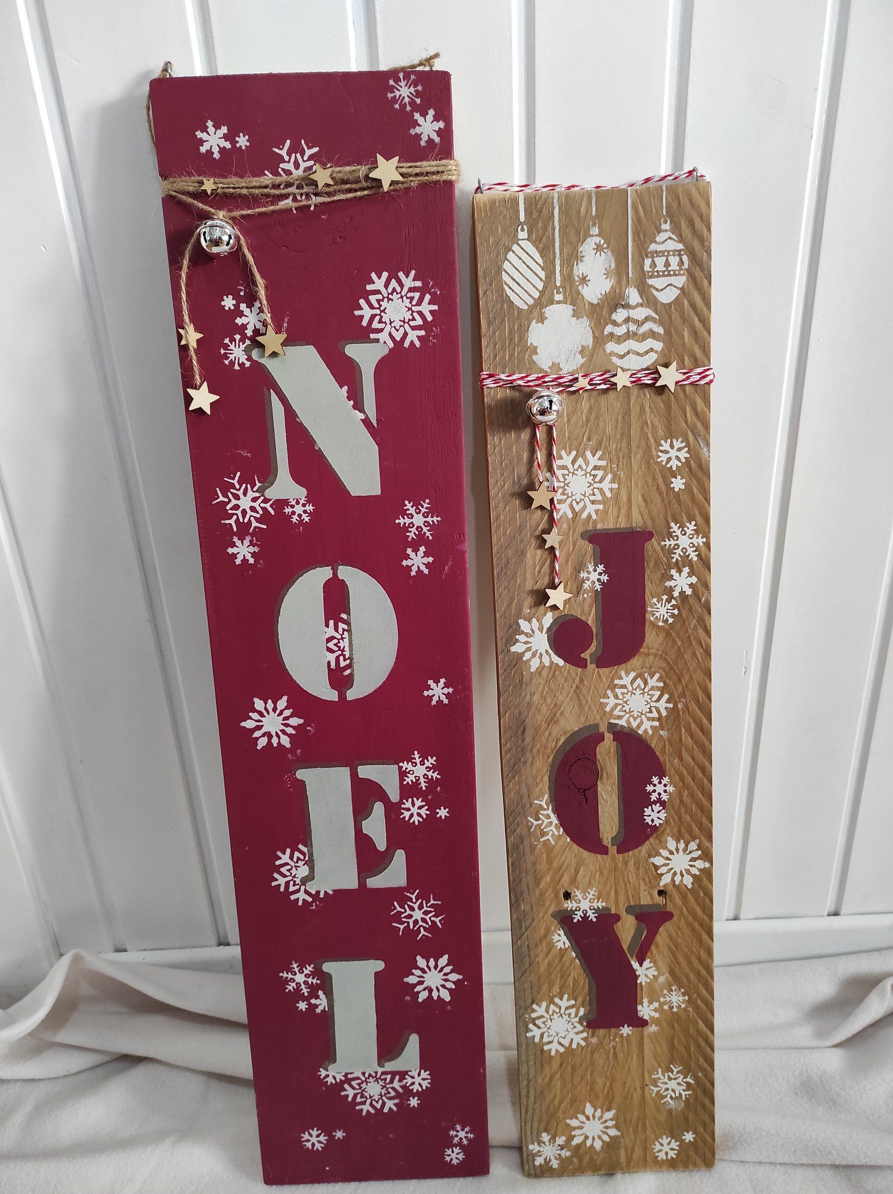 Tavole verticali dipinte con le scritte NOEL e JOY e fiocchi di neve a stencil