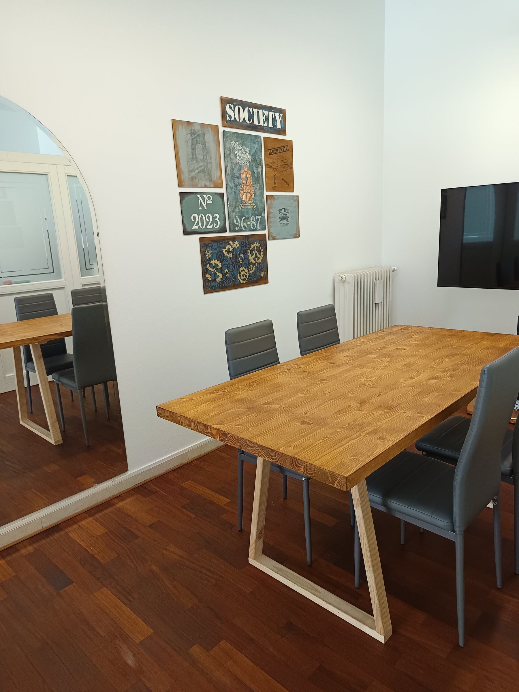 Sala riunioni con tavolo in legno e la composizione di tavole dipinte sulla parete